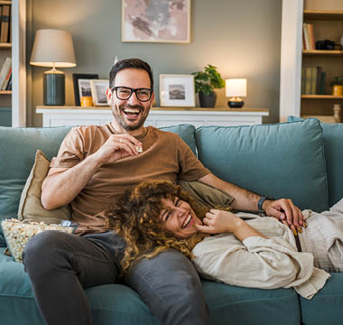 Pärchen liegt lächelnd auf der Couch